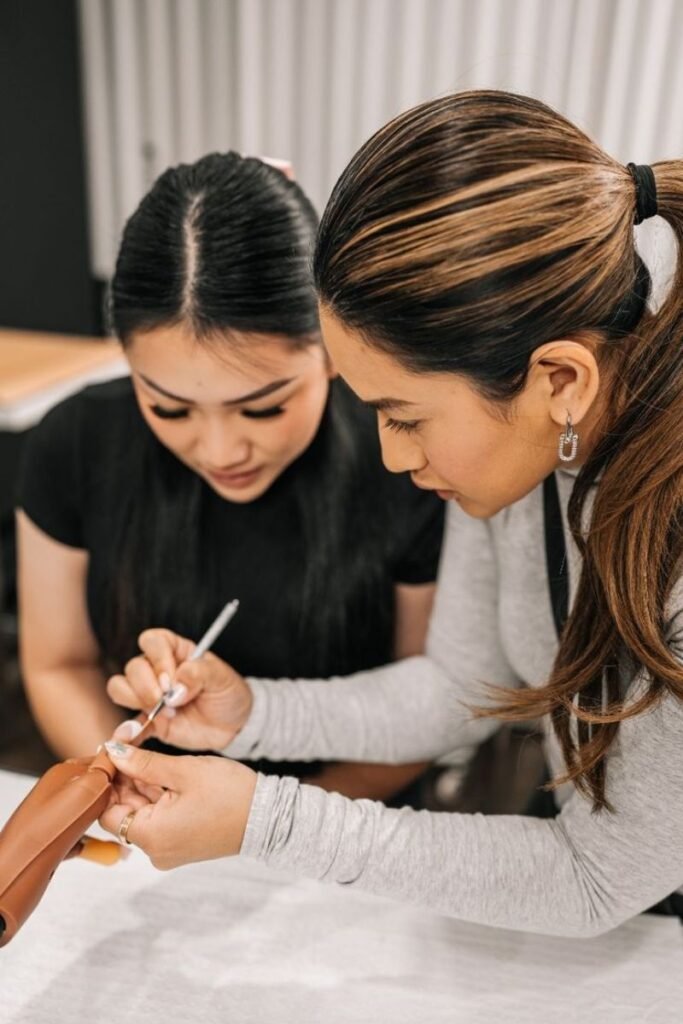 nail technician applying acrylic powder on long nail extension at salon