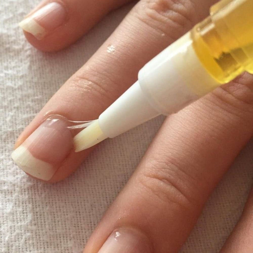 "woman applying cuticle oil to maintain acrylic nails refill at home"