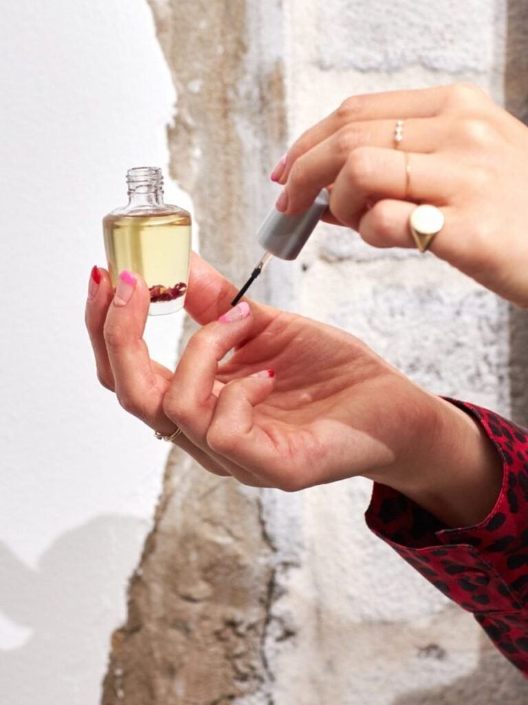 woman applying cuticle oil to long acrylic nails for proper nail care routine
