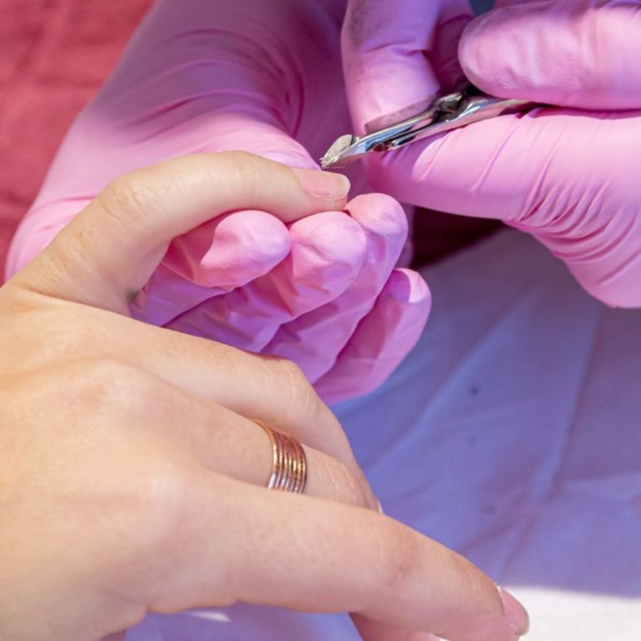 gently removing softened acrylic nails with cuticle pusher